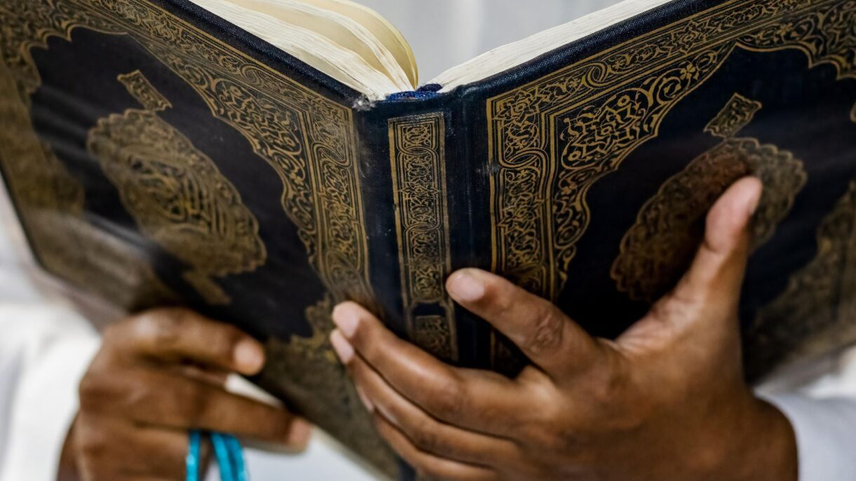 Close-up of a person holding and reading the Qur’an, symbolizing the dedication to learn Quran online with Tajweed.