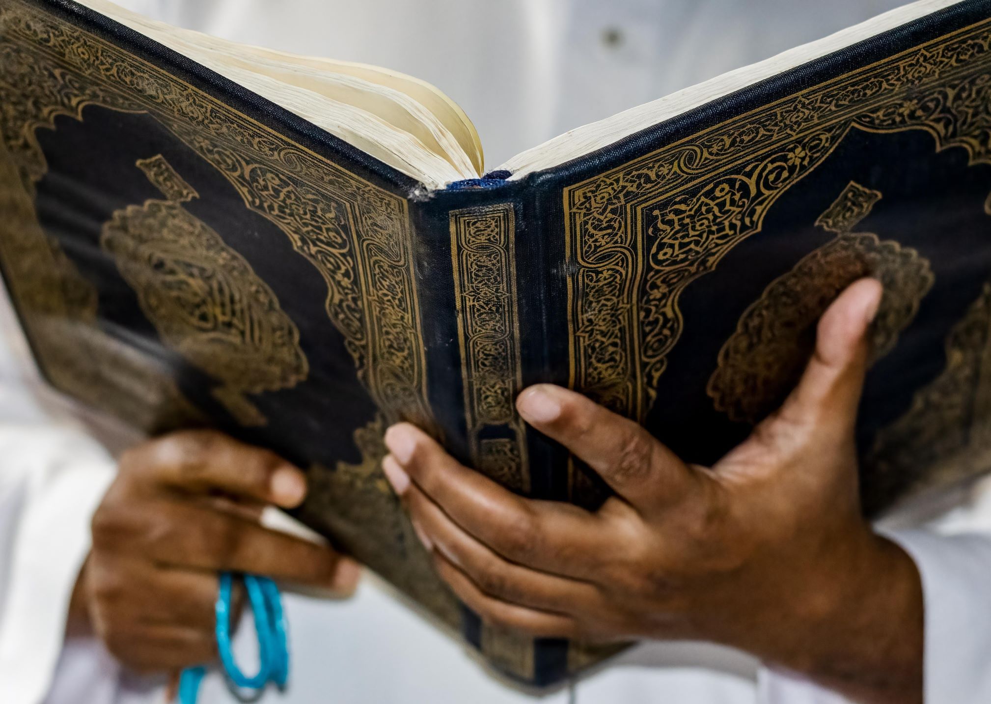 Close-up of a person holding and reading the Qur’an, symbolizing the dedication to learn Quran online with Tajweed.