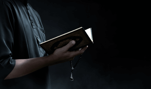 A man holding the Quran in his hand during Quran classes online for beginners
